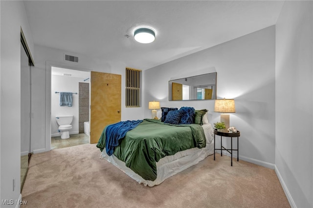 carpeted bedroom with baseboards, visible vents, and ensuite bathroom