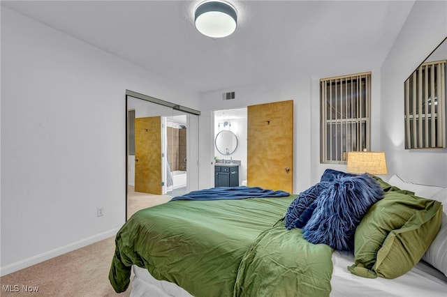 bedroom with carpet, visible vents, a barn door, ensuite bath, and baseboards