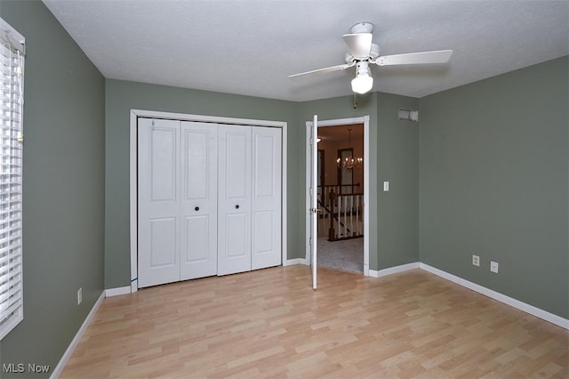 unfurnished bedroom with a textured ceiling, a closet, light wood-type flooring, and baseboards