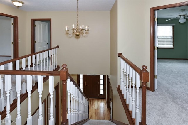 staircase with carpet flooring, baseboards, and ceiling fan with notable chandelier