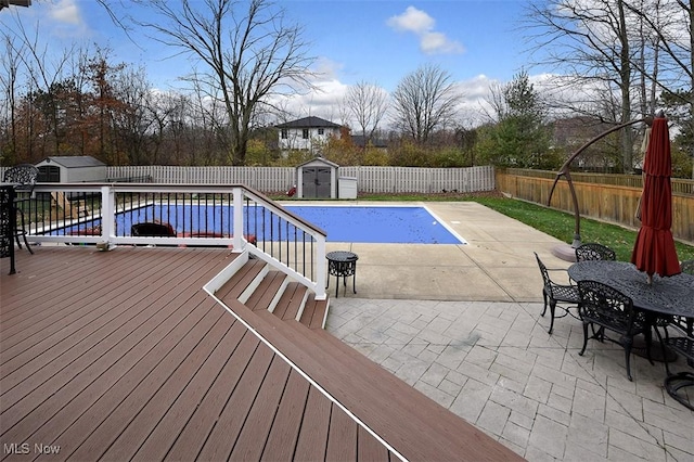 view of swimming pool with outdoor dining space, a shed, a fenced backyard, and an outdoor structure