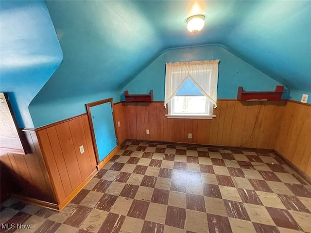 bonus room with lofted ceiling, wainscoting, wood walls, and tile patterned floors