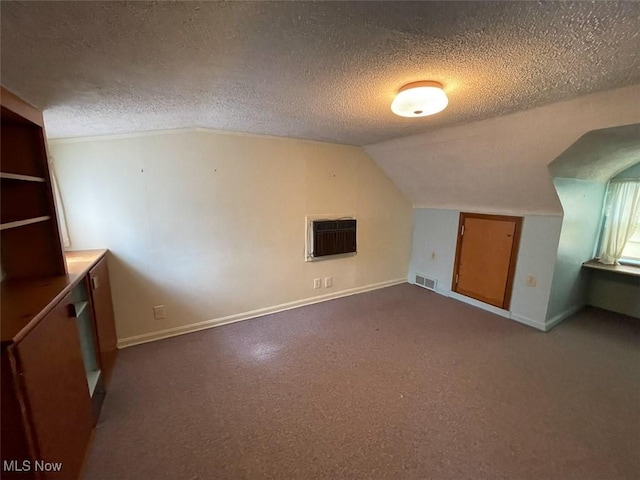 additional living space with lofted ceiling, baseboards, visible vents, and a textured ceiling