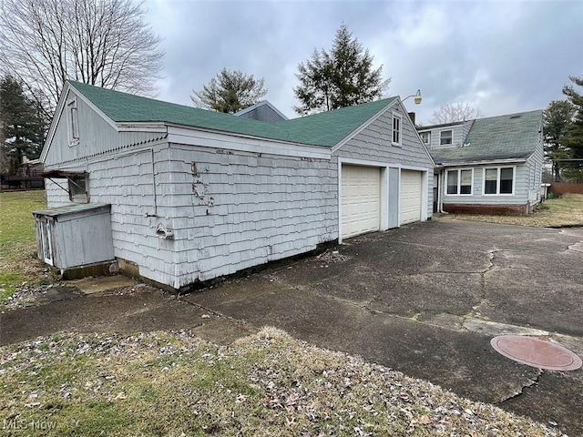 view of side of home featuring a garage and aphalt driveway