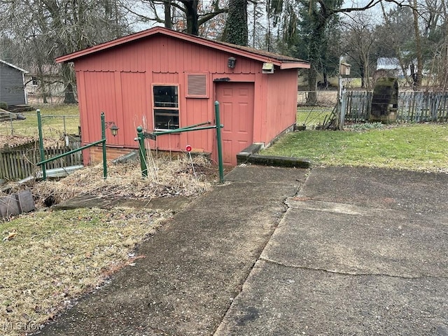 view of outdoor structure with fence and an outbuilding