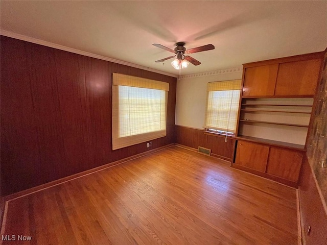 spare room featuring light wood-style floors, visible vents, plenty of natural light, and a ceiling fan