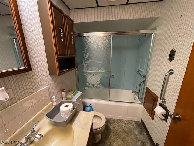 bathroom featuring bath / shower combo with glass door, vanity, toilet, and wallpapered walls