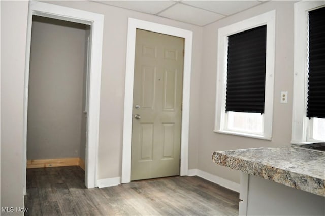 interior space featuring wood finished floors, a paneled ceiling, and baseboards