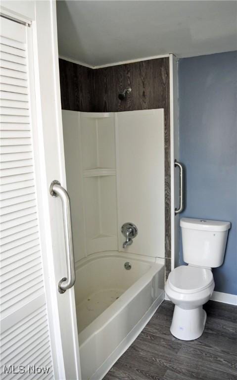 bathroom featuring toilet, baseboards, wood finished floors, and bathing tub / shower combination