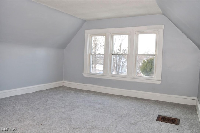 additional living space featuring baseboards, plenty of natural light, visible vents, and carpet flooring