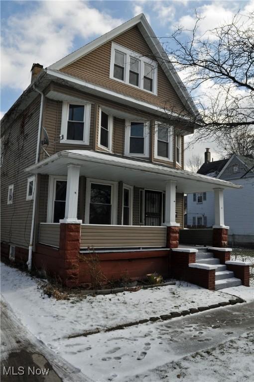 view of front facade featuring covered porch and a chimney