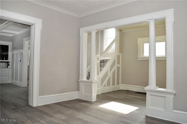 unfurnished room featuring stairs, ornate columns, and wood finished floors