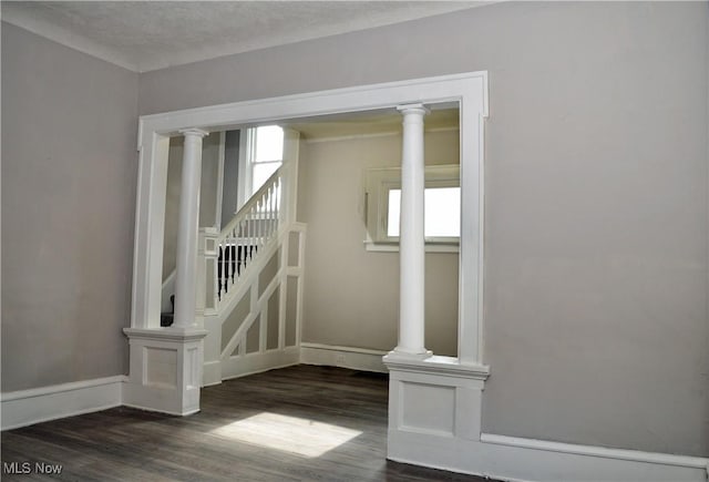 stairs featuring decorative columns, baseboards, and wood finished floors