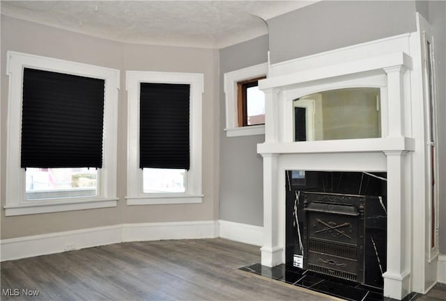 unfurnished living room with a textured ceiling, wood finished floors, and baseboards