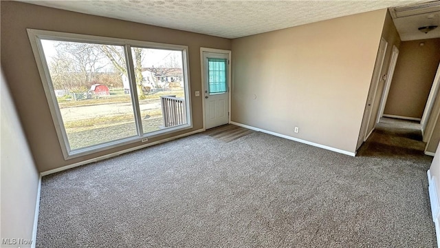 unfurnished room with a textured ceiling, carpet flooring, and baseboards