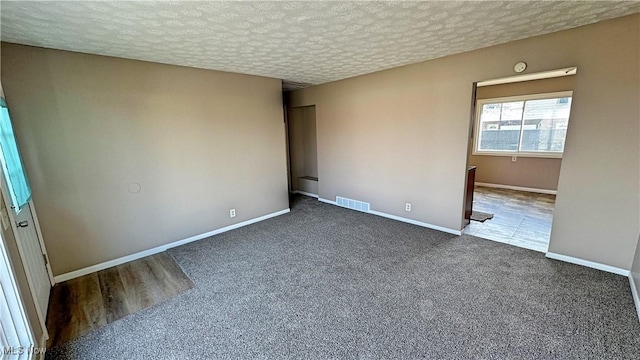 interior space featuring baseboards, visible vents, a textured ceiling, and carpet flooring