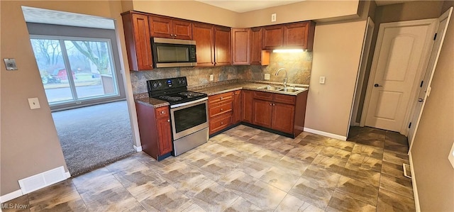 kitchen featuring light carpet, visible vents, decorative backsplash, stainless steel appliances, and a sink