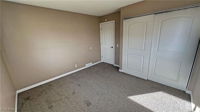 unfurnished bedroom featuring a closet, dark carpet, and baseboards