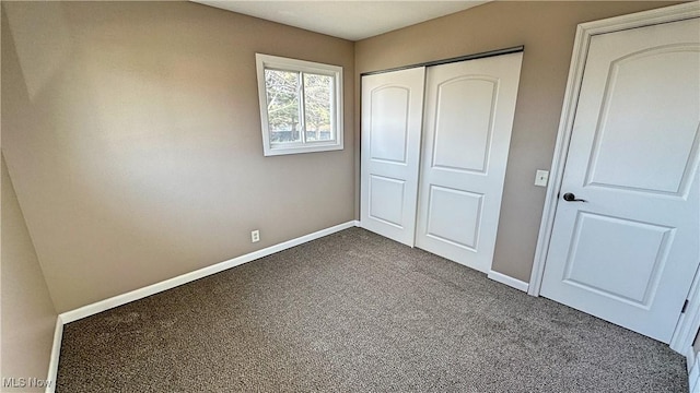 unfurnished bedroom with dark colored carpet, a closet, and baseboards