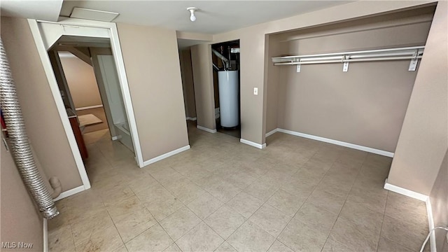 unfurnished bedroom featuring water heater and baseboards