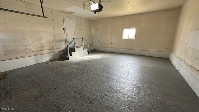 garage with a garage door opener and concrete block wall