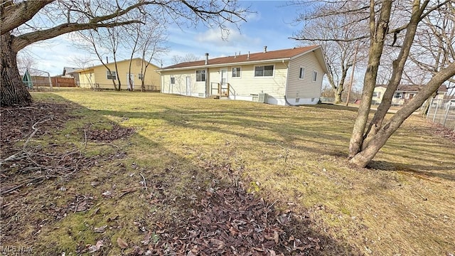 rear view of house featuring a yard and fence