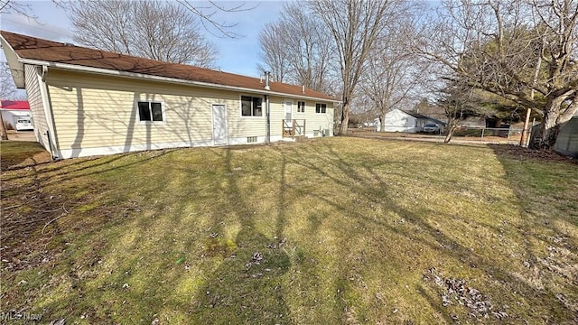 rear view of property featuring a yard and fence