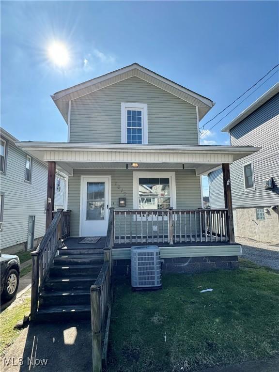 view of front of home with covered porch, central AC, and a front yard