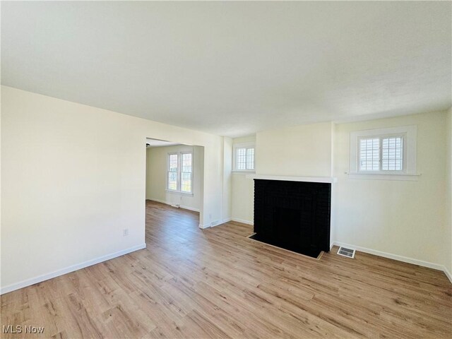 1019 Trenton, Toronto, OH 43964 - unfurnished living room featuring a fireplace with flush hearth, visible vents, light wood-style flooring, and baseboards