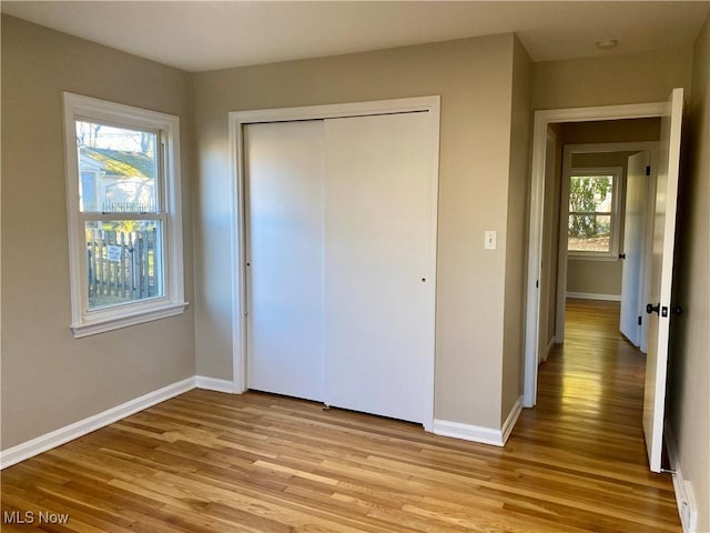 unfurnished bedroom with light wood-style flooring, baseboards, and a closet