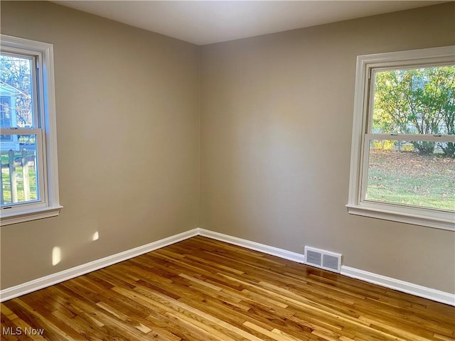 unfurnished room with a wealth of natural light, visible vents, and baseboards