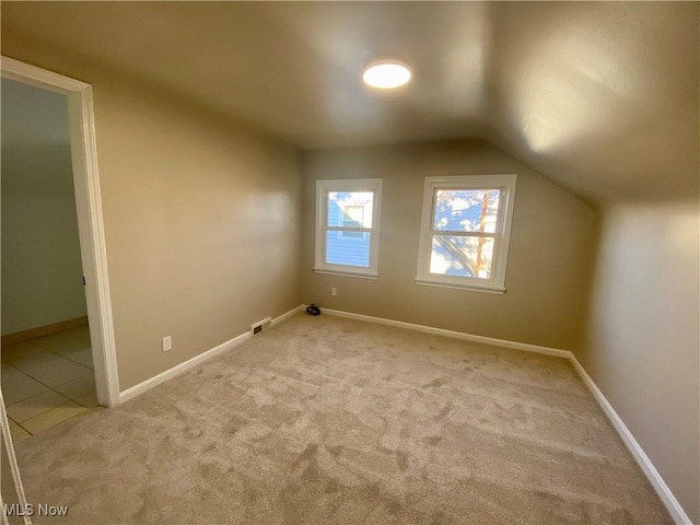 additional living space with carpet flooring, vaulted ceiling, visible vents, and baseboards