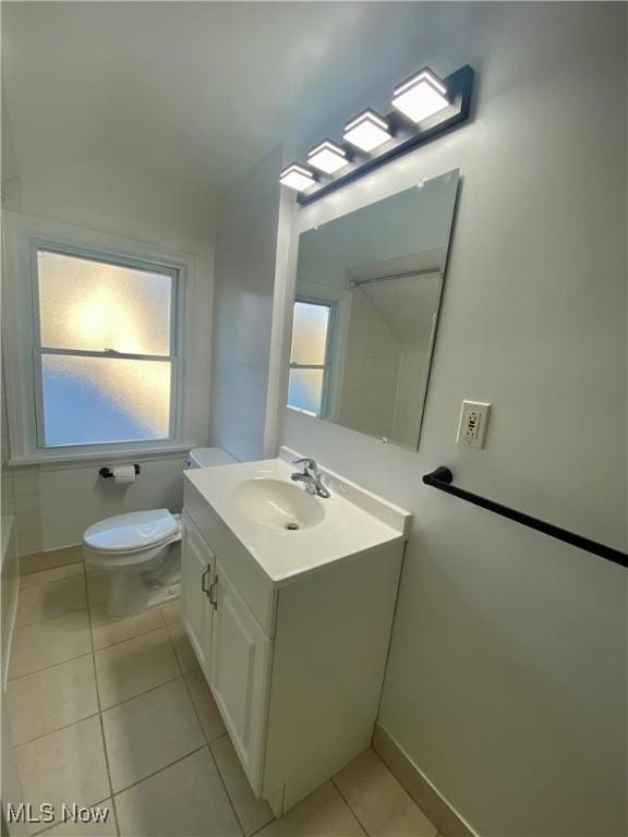 bathroom featuring a washtub, toilet, vanity, baseboards, and tile patterned floors