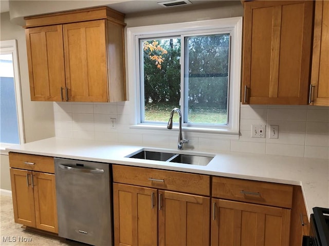 kitchen featuring light countertops, brown cabinets, dishwasher, and a sink