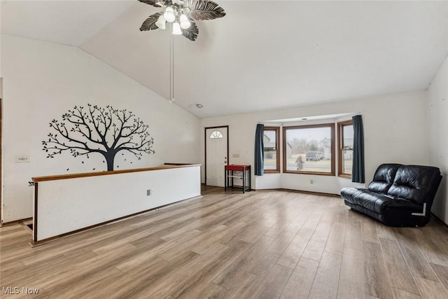 living area featuring a ceiling fan, vaulted ceiling, and light wood finished floors