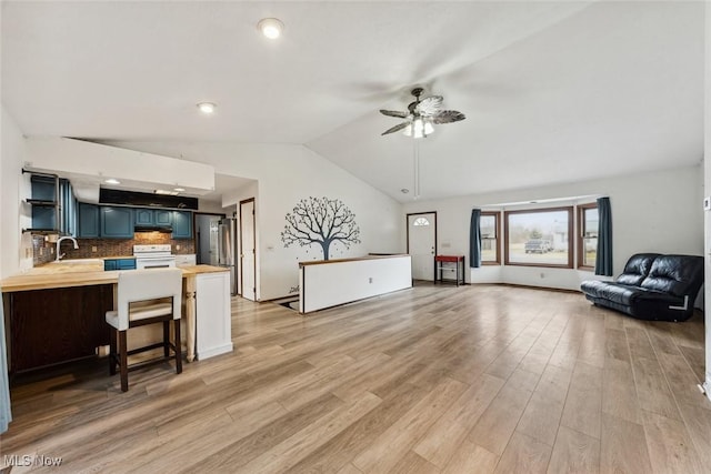 kitchen featuring butcher block counters, open floor plan, blue cabinets, a peninsula, and white electric range