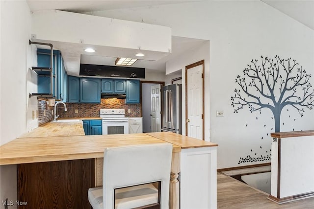 kitchen featuring under cabinet range hood, blue cabinets, a peninsula, high end fridge, and white range with electric cooktop