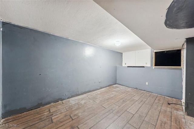 finished basement featuring a textured ceiling and wood finished floors