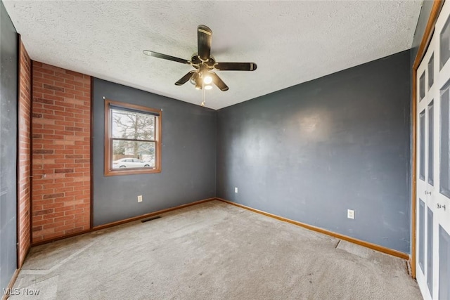 carpeted empty room featuring a ceiling fan, visible vents, a textured ceiling, and baseboards