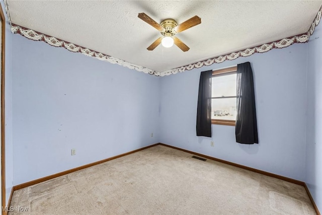 carpeted spare room featuring a textured ceiling, ceiling fan, visible vents, and baseboards