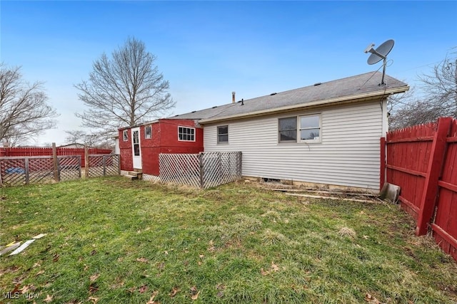 rear view of house featuring a fenced backyard and a lawn