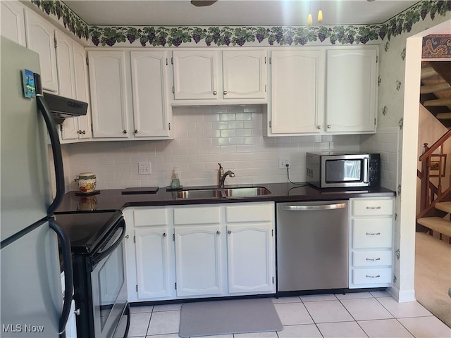 kitchen with tasteful backsplash, white cabinets, dark countertops, stainless steel appliances, and a sink