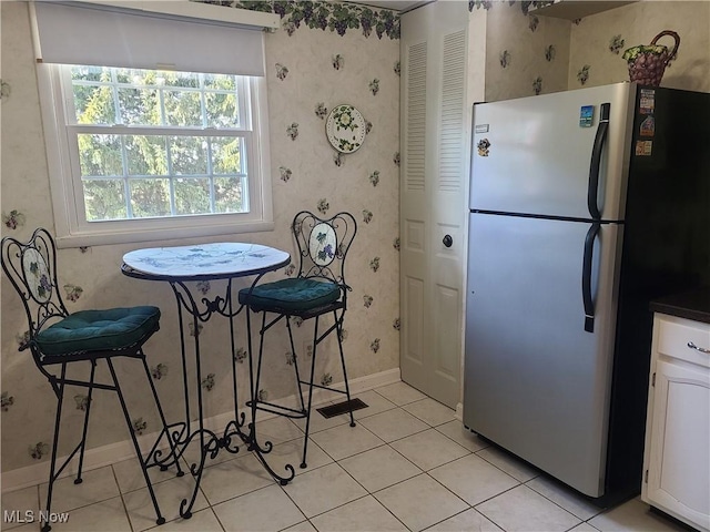 dining space with light tile patterned floors, baseboards, and wallpapered walls