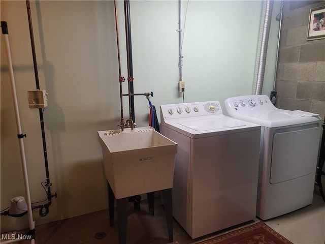 washroom featuring a sink, laundry area, washing machine and dryer, and concrete block wall