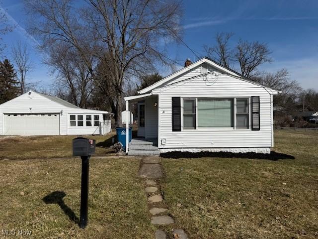 view of front of home with a garage, an outbuilding, a porch, and a front lawn