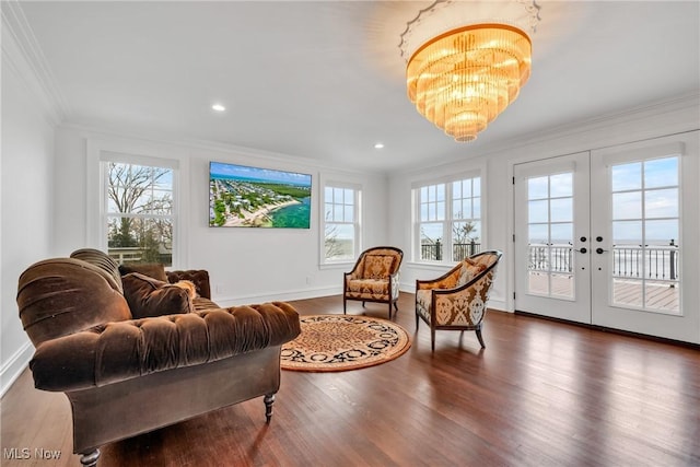 living area featuring french doors, ornamental molding, an inviting chandelier, and wood finished floors