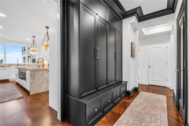 mudroom featuring crown molding, baseboards, a notable chandelier, and a sink