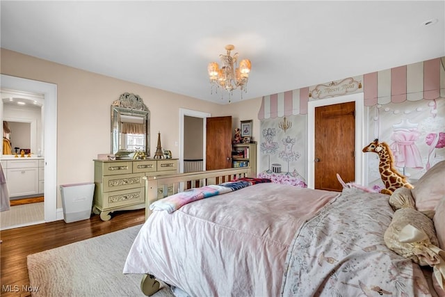 bedroom with wood finished floors, ensuite bathroom, a notable chandelier, and baseboards