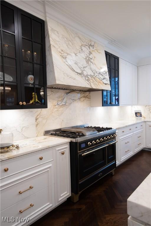 kitchen featuring white cabinets, glass insert cabinets, ornamental molding, and double oven range