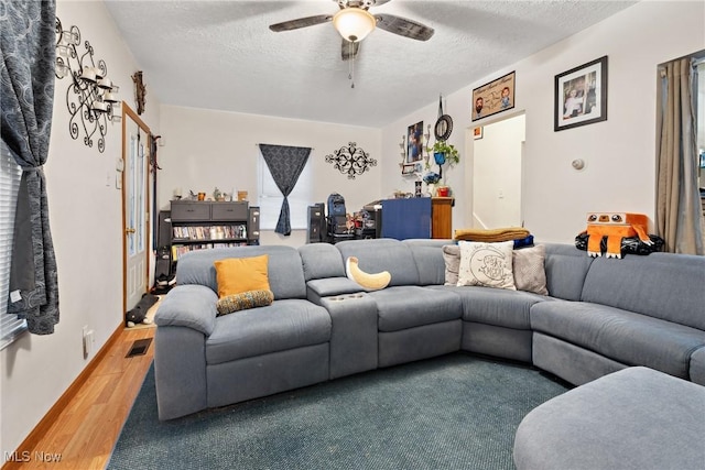 living area featuring ceiling fan, a textured ceiling, visible vents, and wood finished floors